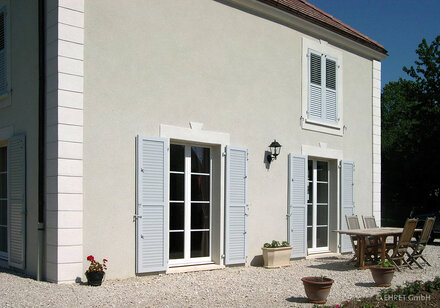 Klassische Klappläden in weiß an den bodentiefen Fenstern eines weißen Einfamilienhauses Klassische Klappläden in weiß an den bodentiefen Fenstern eines weißen Einfamilienhauses