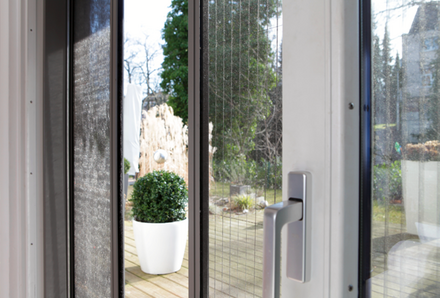 Detailansicht eines Insektenschutz-Schiebetürgitters an einer weißen Balkontüre. Ausführungen: als Insektenschutz-Schiebetür, -Pendeltür, -Drehtür oder -Plisséetür. Detailansicht eines Insektenschutz-Schiebetürgitters an einer weißen Balkontüre. Ausführungen: als Insektenschutz-Schiebetür, -Pendeltür, -Drehtür oder -Plisséetür.